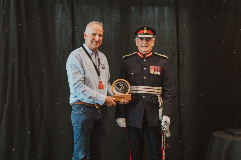Man receiving award next to man dressed in uniform.