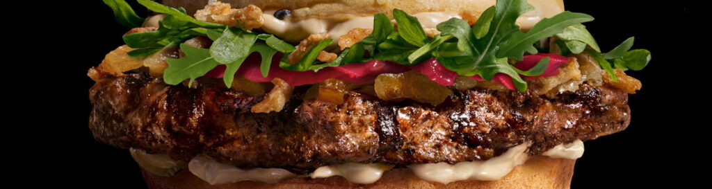 A picture of the Wagyu: a burger in a bun with lettuce and caramilsed onions.