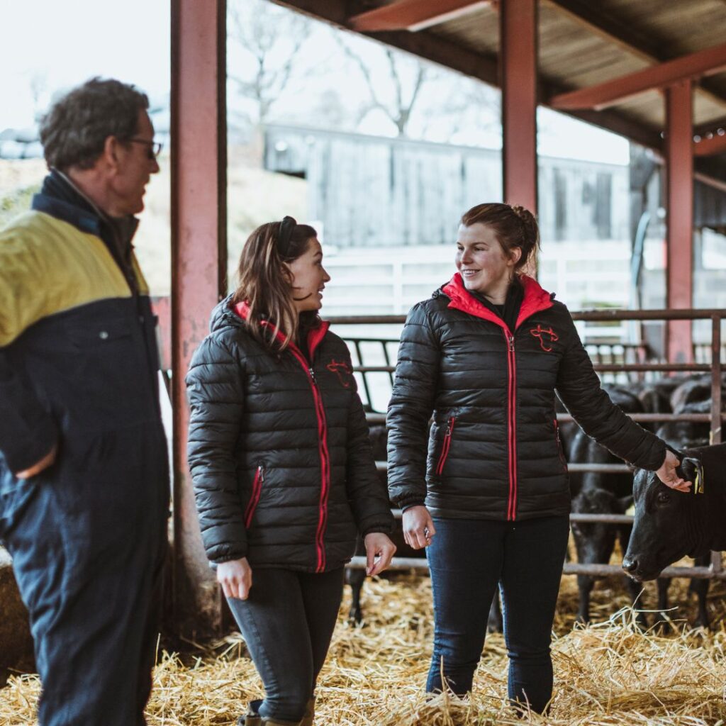 Man and two women engaged in conversation in a cattle shed