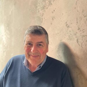 Man in blue sweater next to a beige wall