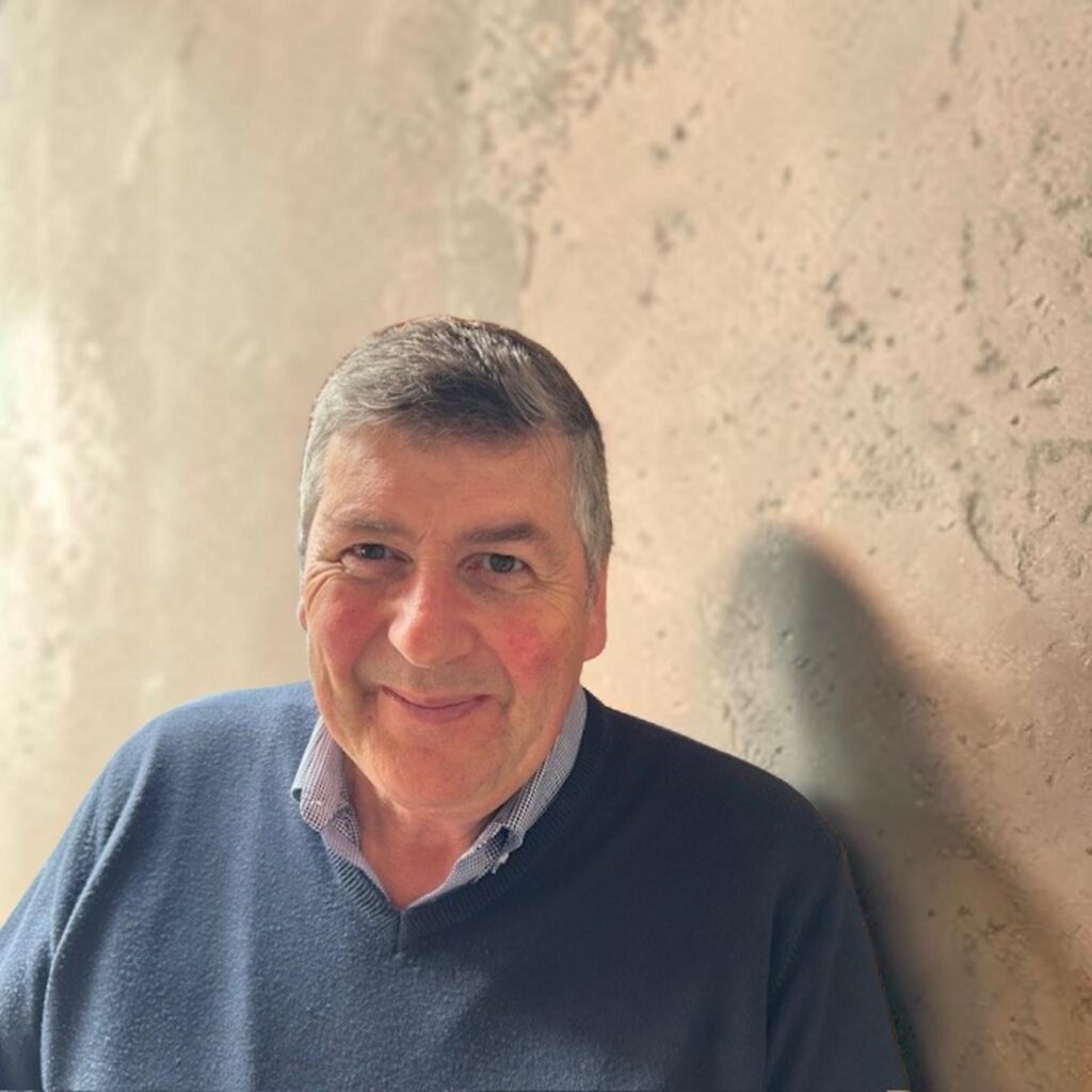 Man in blue sweater standing next to the wall